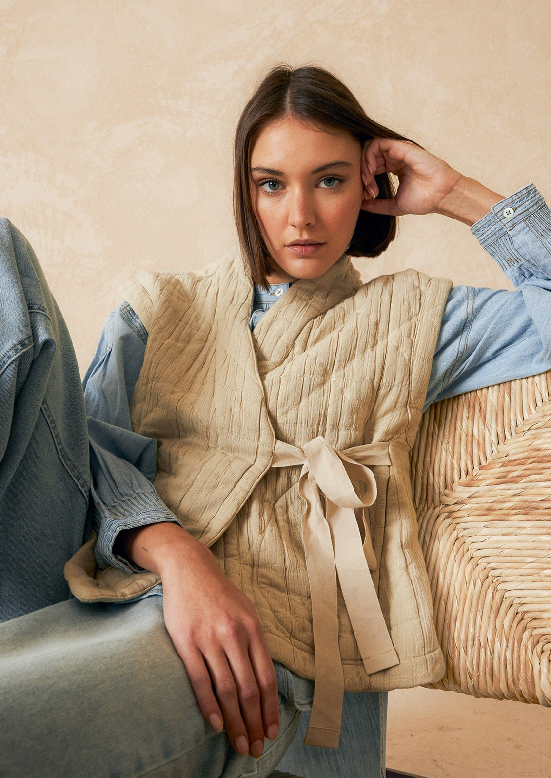 A tie front vest in cream with quilted texture and sash tie front.