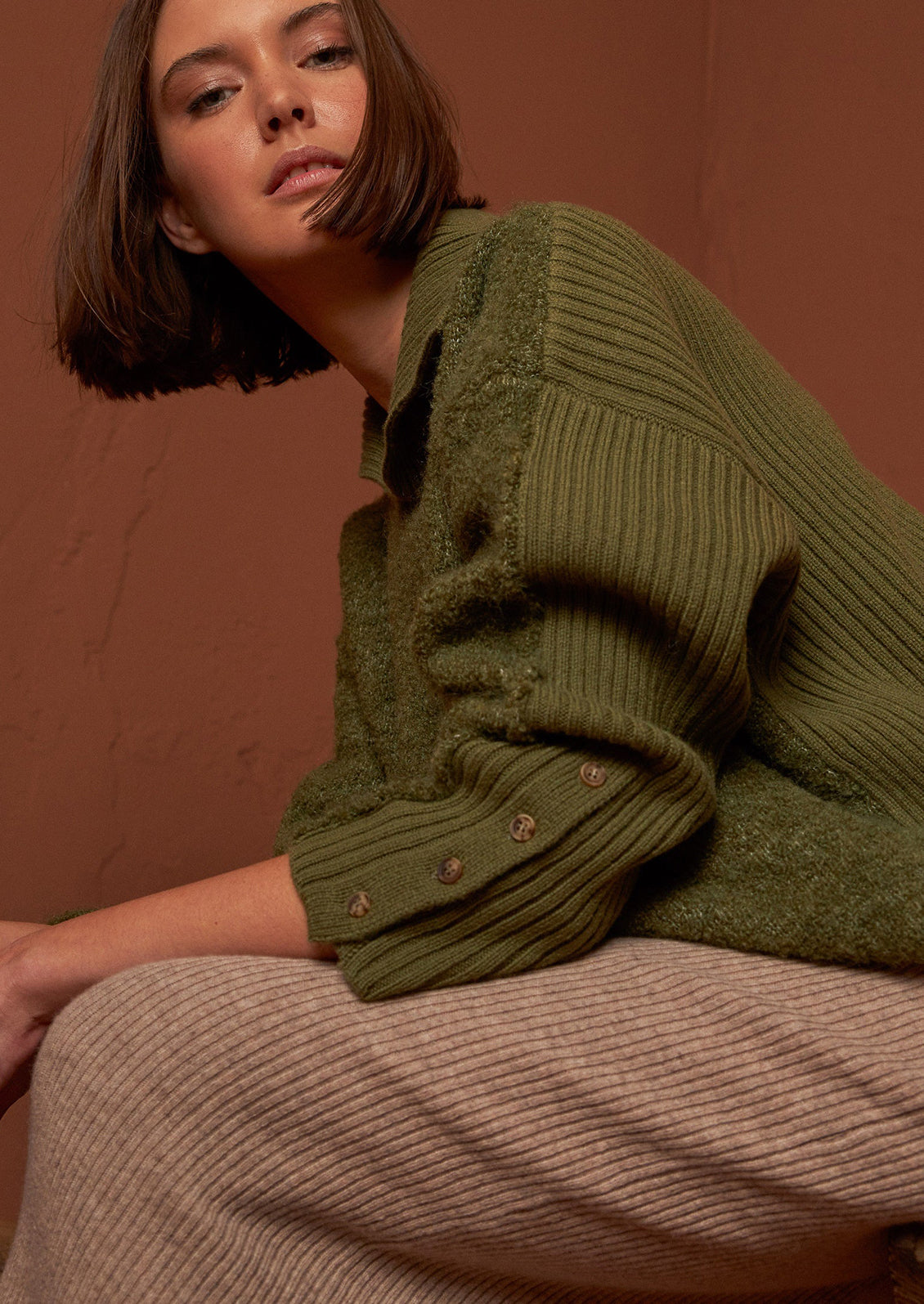A woman wearing a polo collar fuzzy army green sweater.