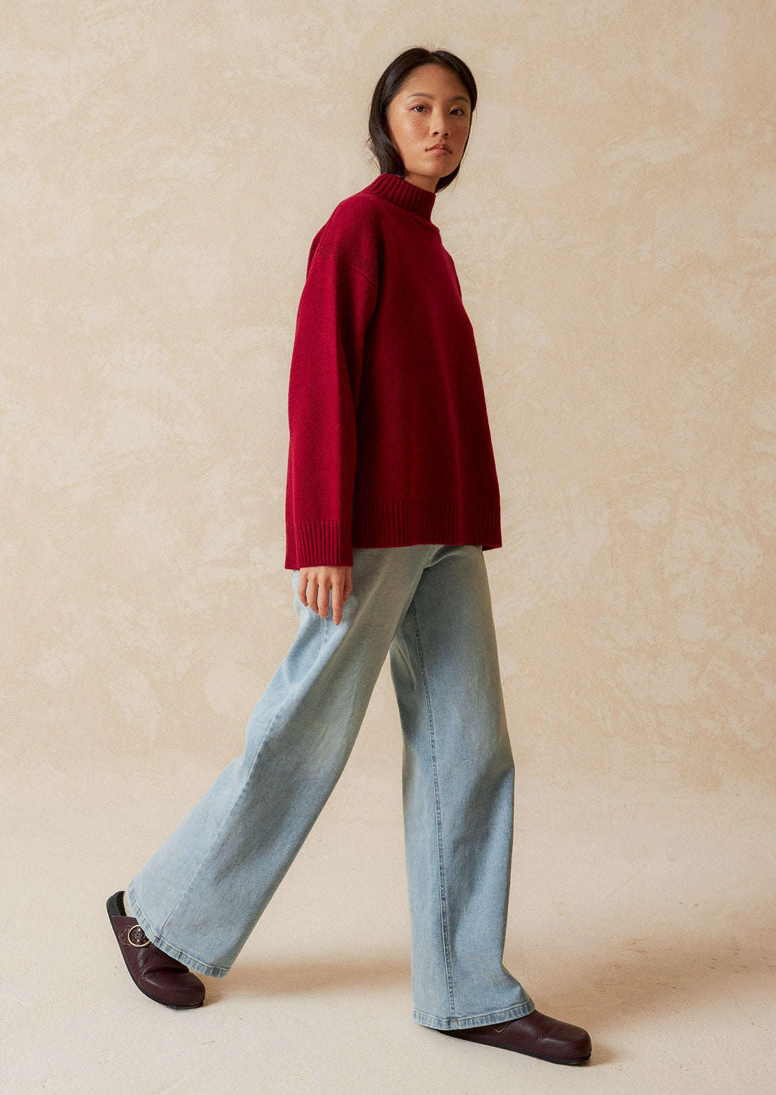 A woman wearing an oversized mockneck sweater.