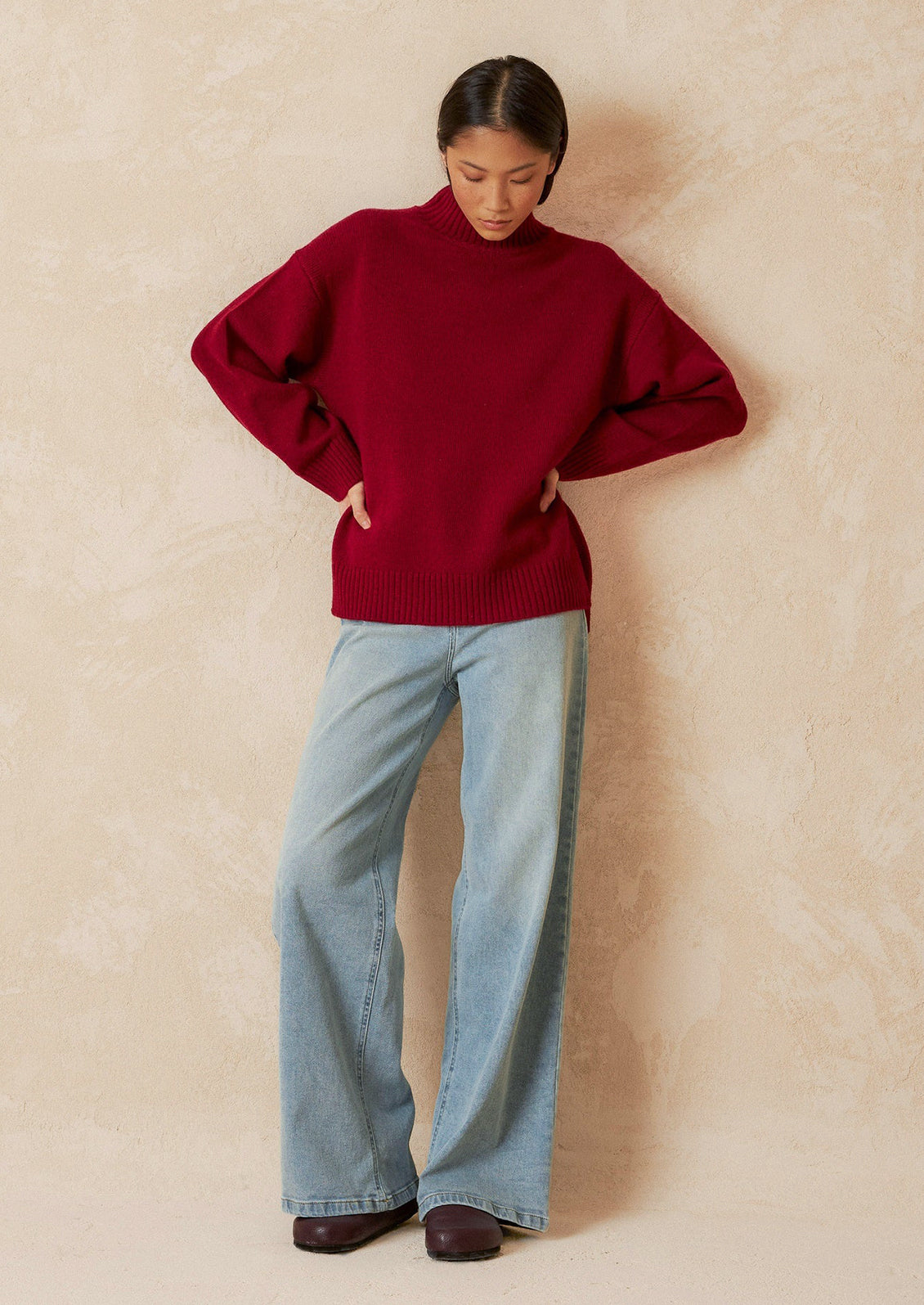 A woman wearing an oversized mockneck sweater.