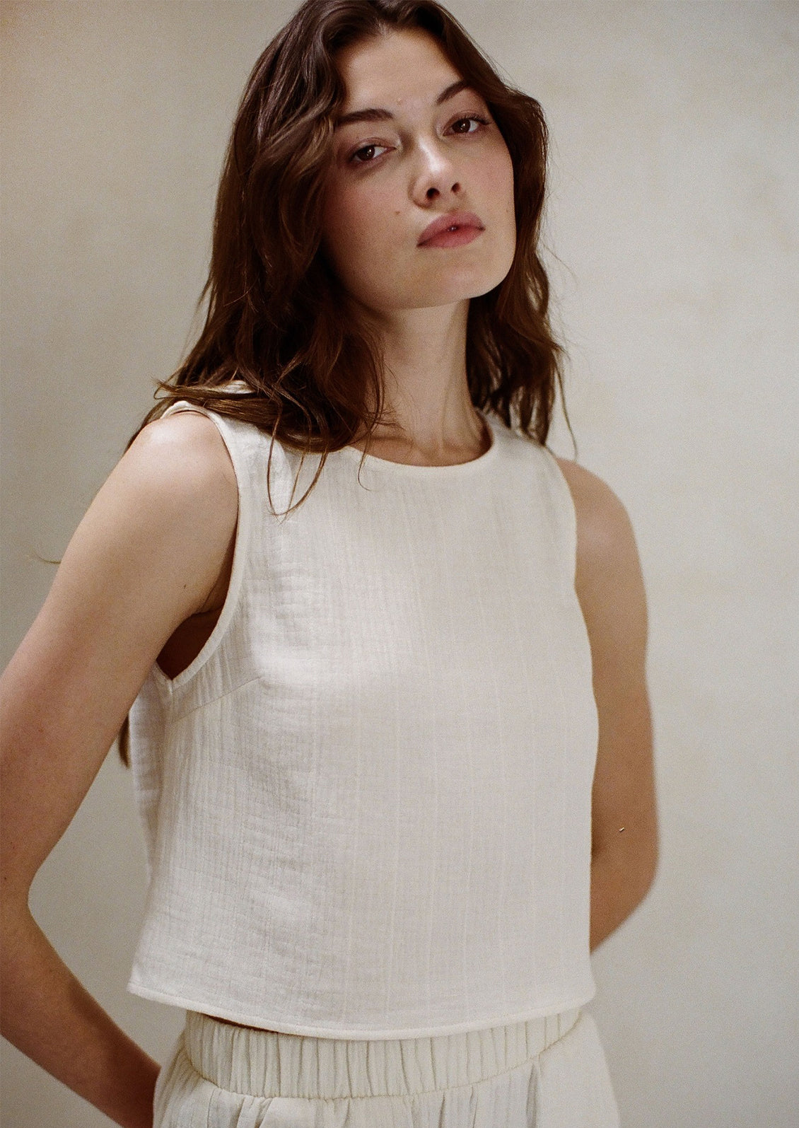 A woman wearing a white gauze tank top.