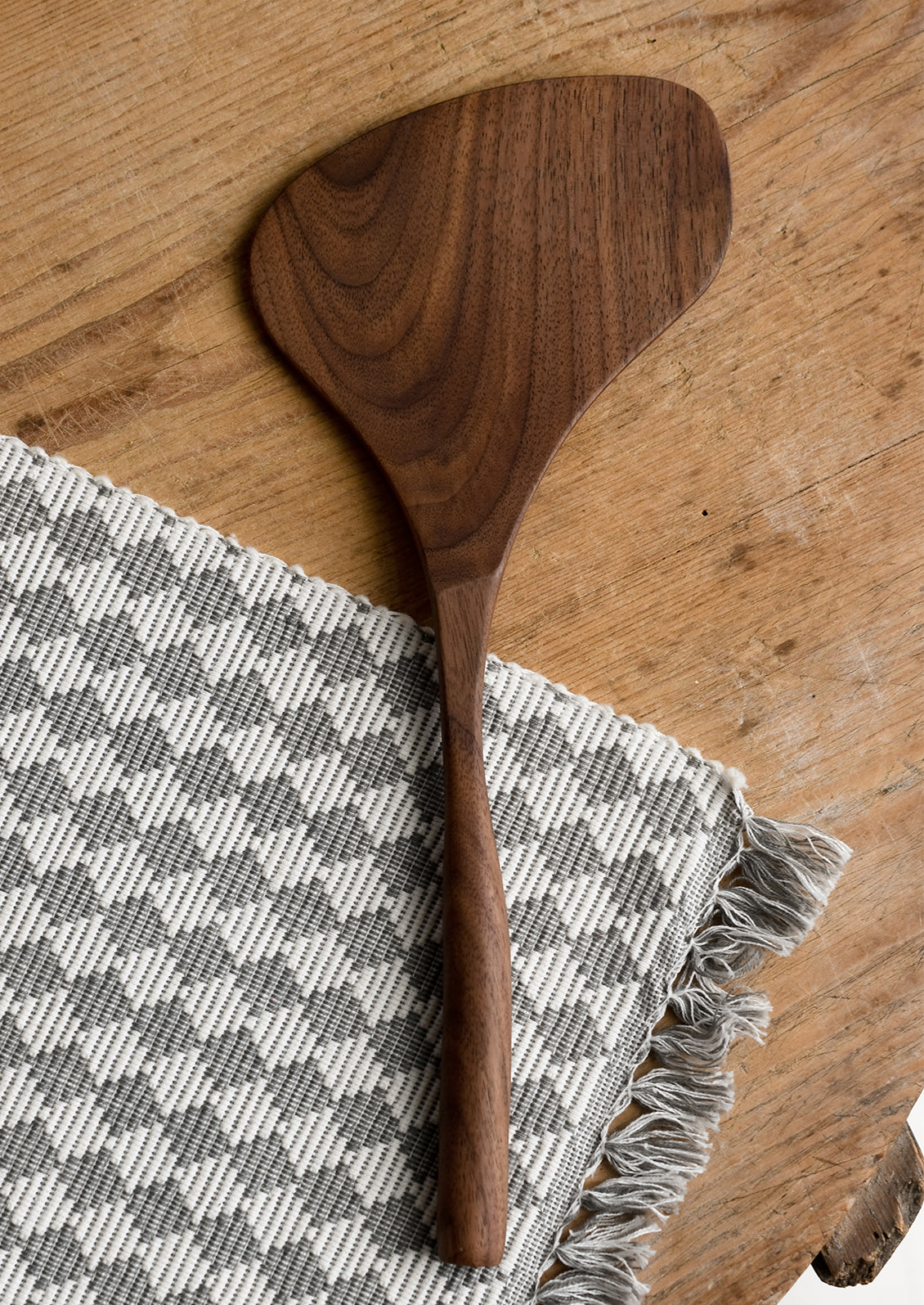 A walnut wood spatula in wide shape.