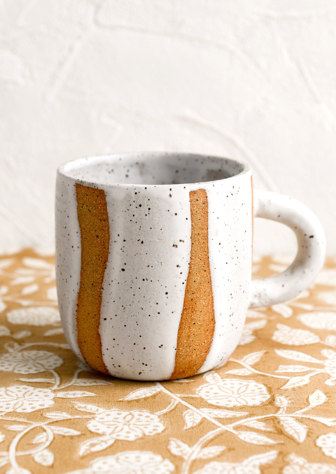 A ceramic mug with wavy stripe pattern in white.