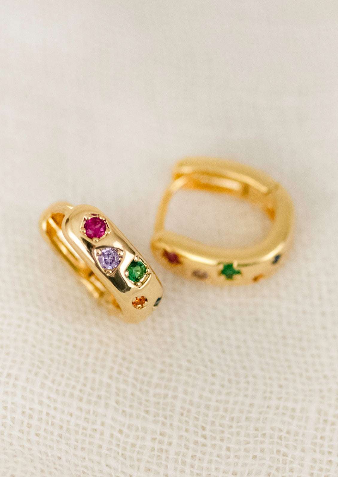 A pair of gold hoops adorned with colorful gems.