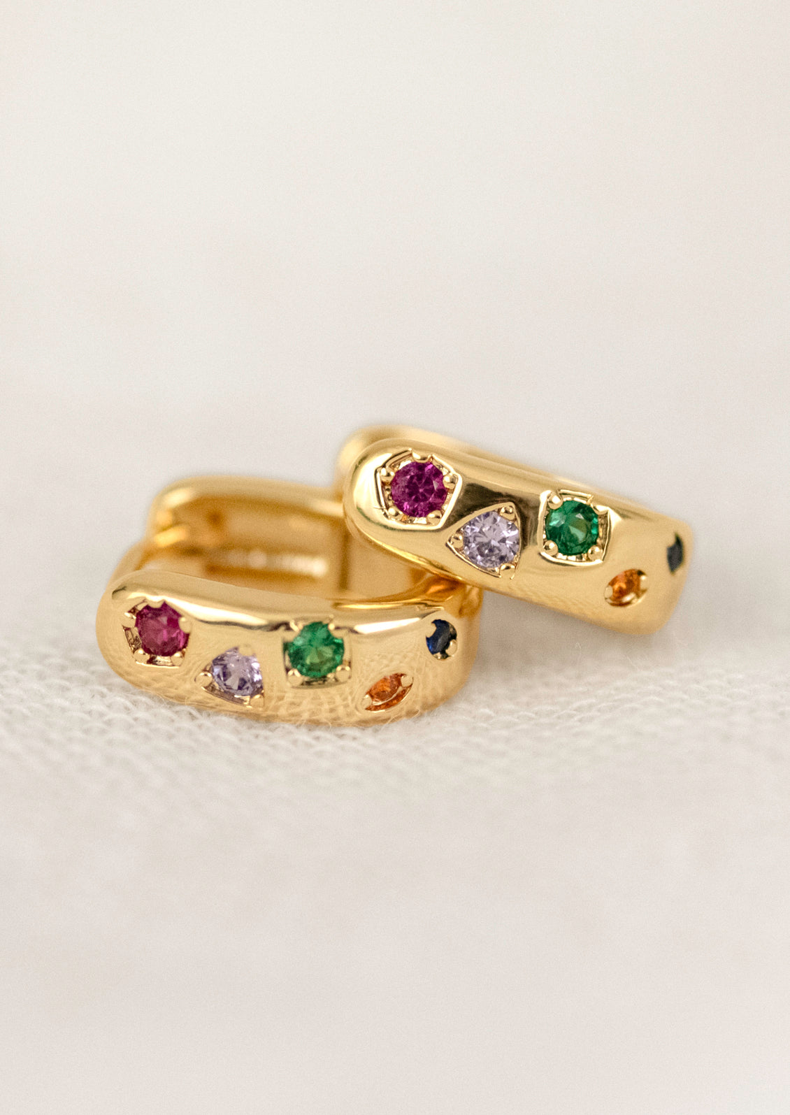A pair of gold hoops adorned with colorful gems.