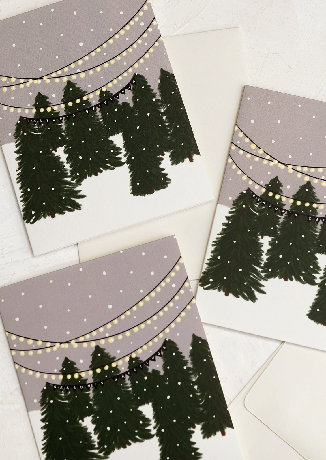A set of holiday greeting cards with illustration of Christmas tree lot, text reads "Season's greetings".