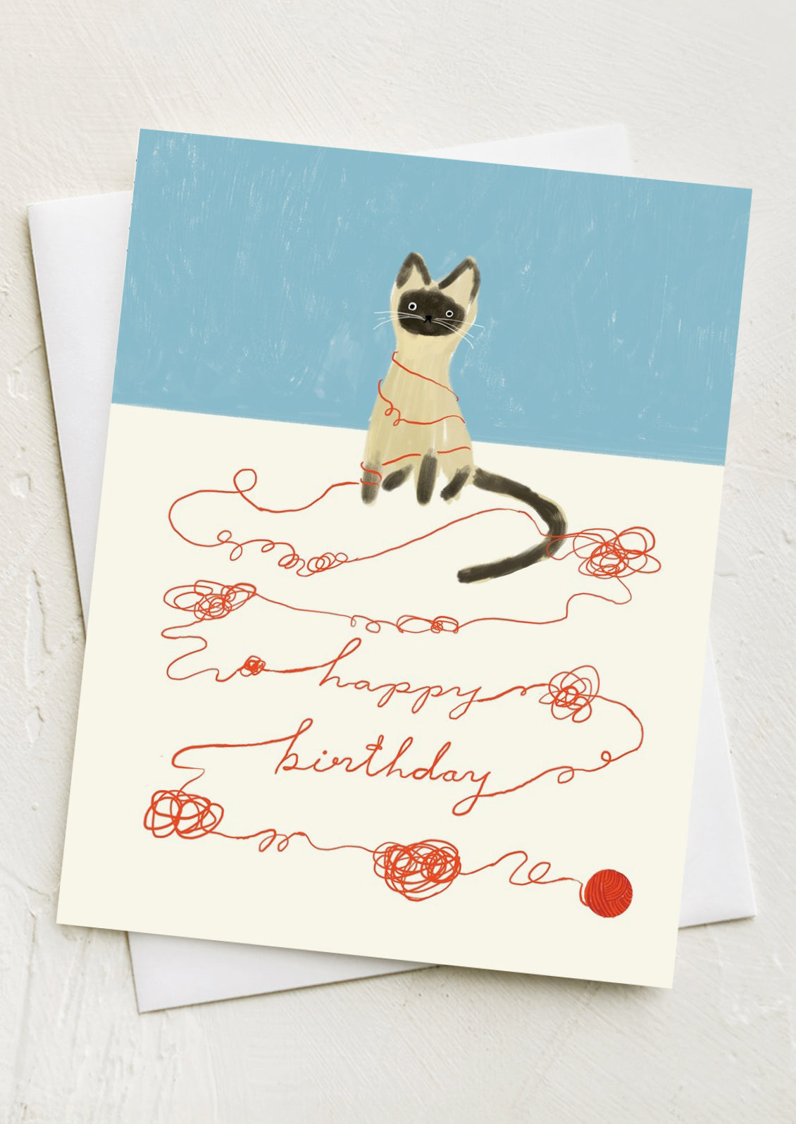 A card with illustration of cat and ball of yarn, loose string spells out "Happy birthday" text.