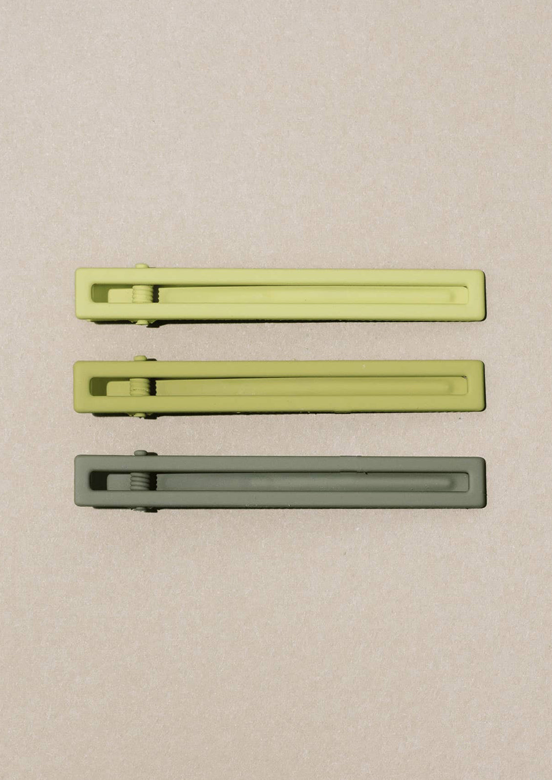A set of three bar-shaped hair clip sets in shades of green.