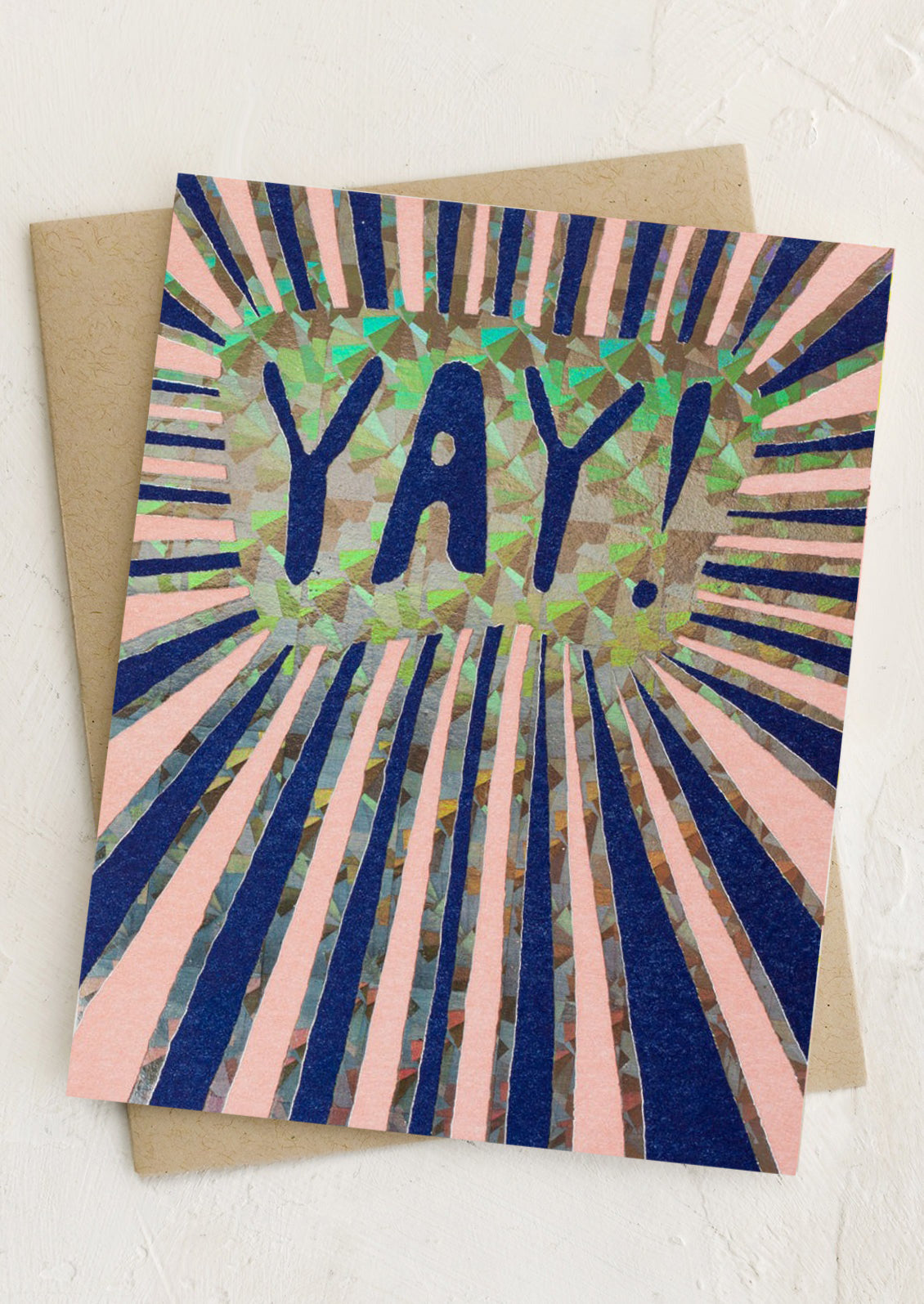 A greeting card with holographic sunburst print, text reads "YAY!".