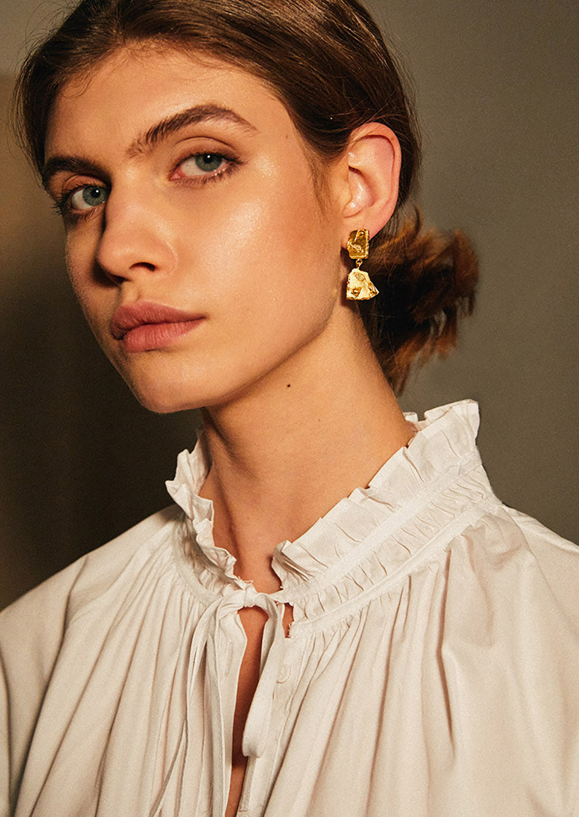 A model wearing gold broken tile earrings.