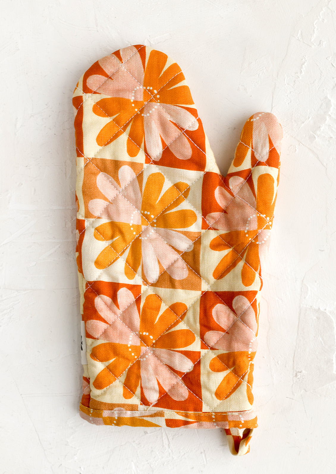 A retro floral print quilted oven mitt in red, yellow, orange and pink.