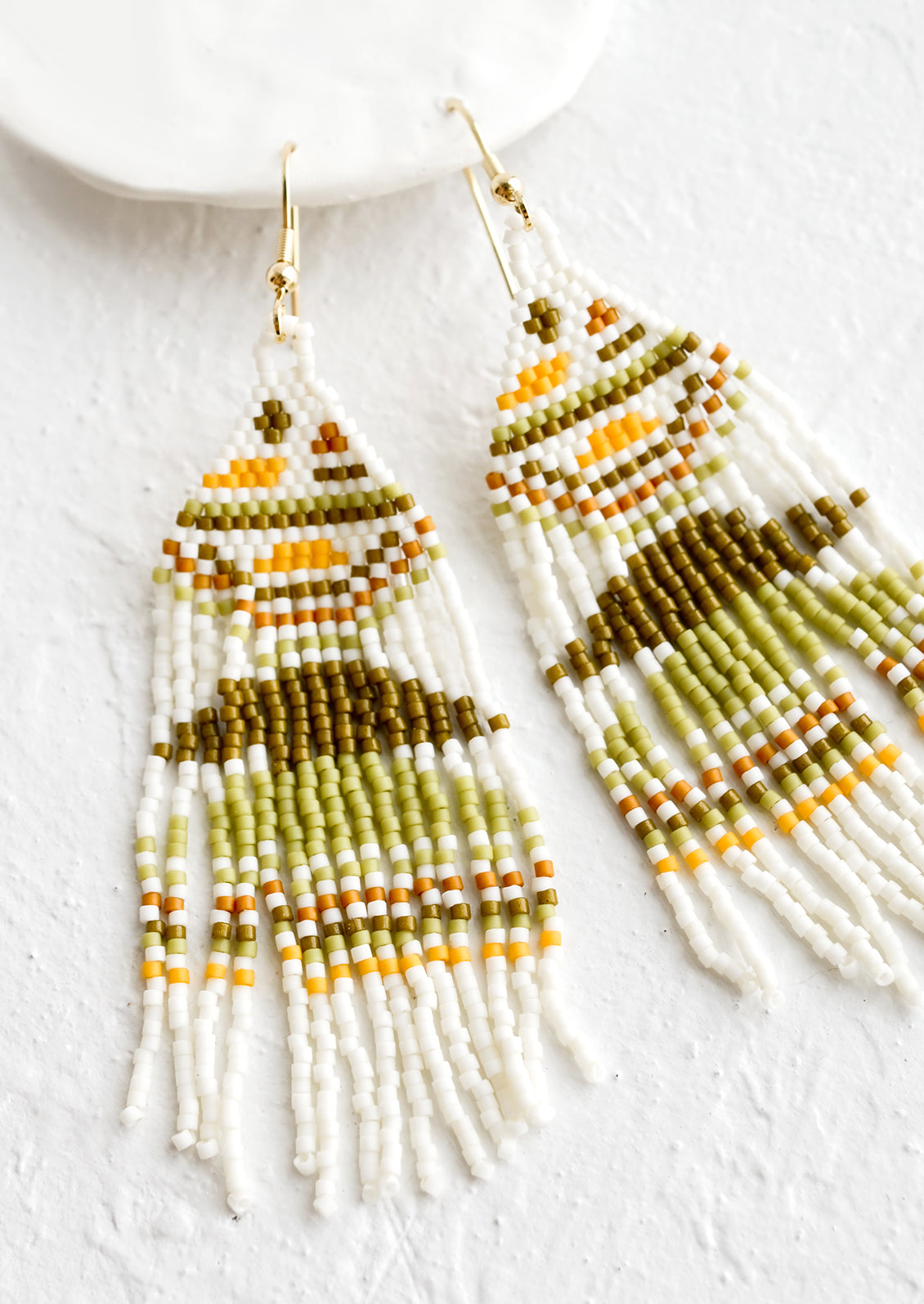 White beaded earrings with design in shades of green, brown and yellow.