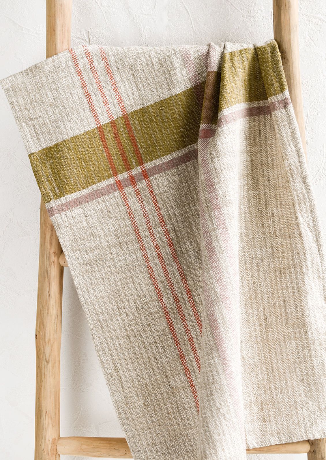 A natural tea towel with orange, ochre and pink plaid pattern.