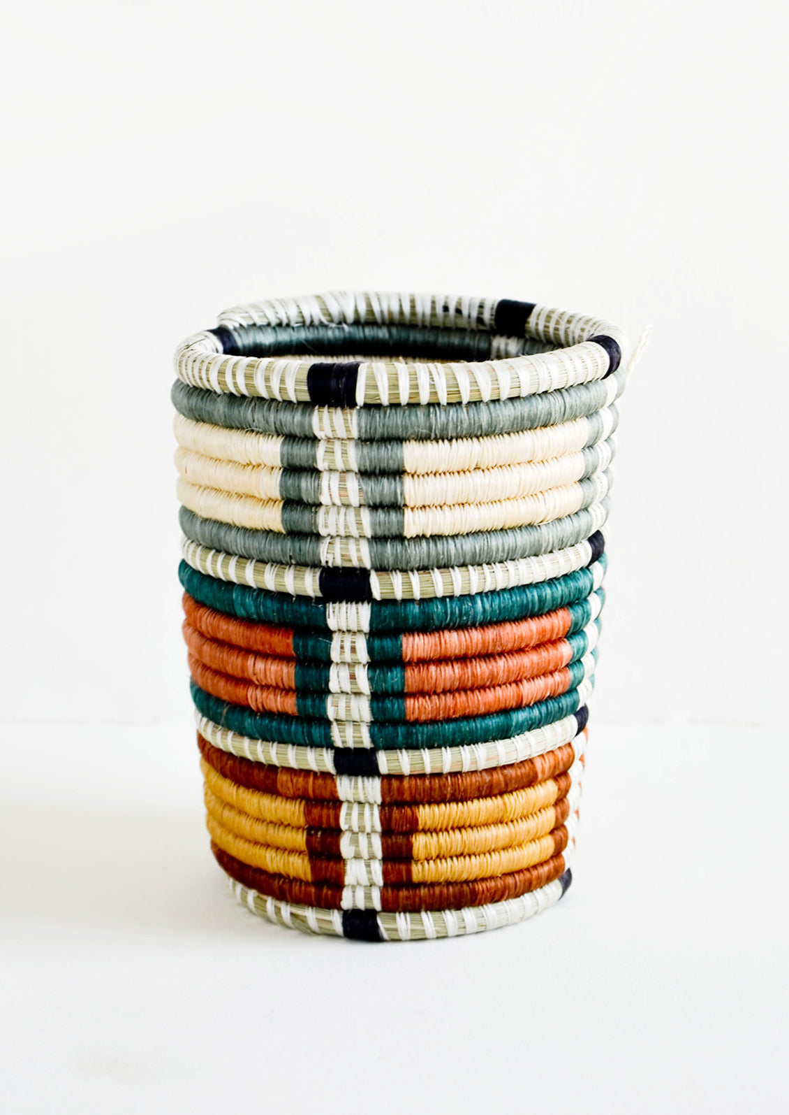 Pencil cup shaped baskets woven from multicolor sweetgrass. Mix of muted colors in a square geometric pattern.