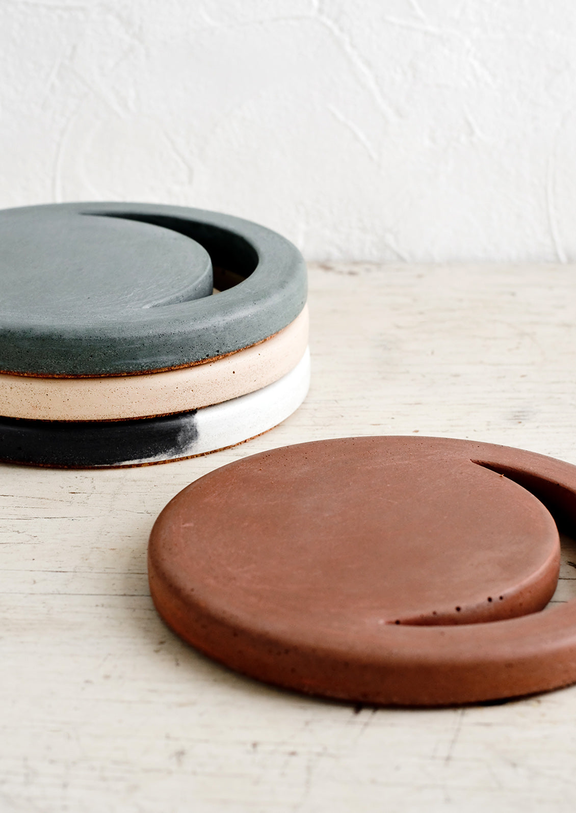 An assortment of round concrete trivets with crescent moon shaped cutout.