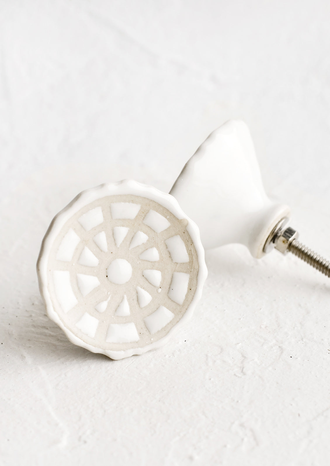 White ceramic cabinet knobs with web-like relief pattern.