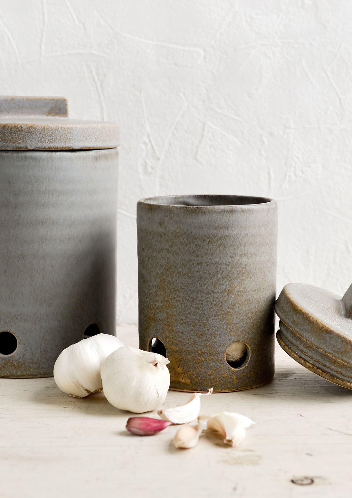 Ceramic kitchen storage jars in two sizes intended for onion and garlic storage.
