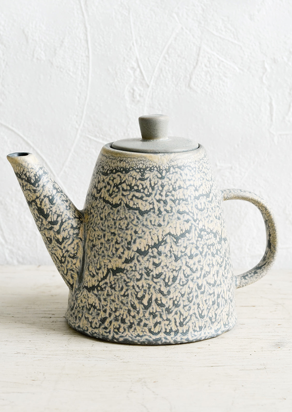 A ceramic lidded teapot in grey and natural speckled glaze.