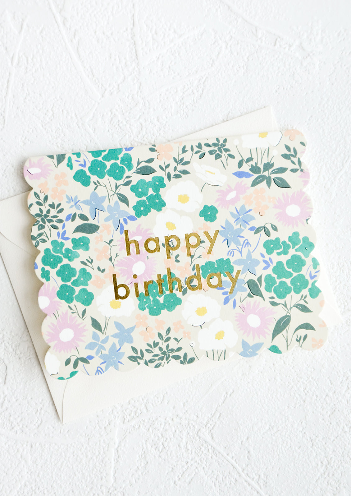 Greeting card with die cut scalloped edges, allover floral print and "Happy birthday" printed in gold