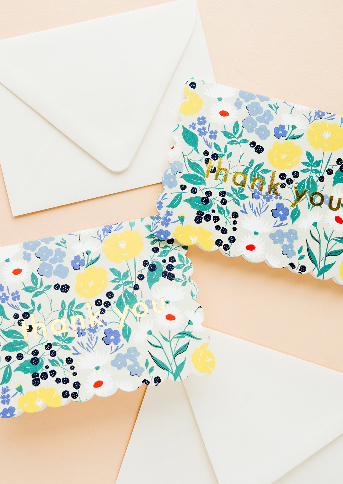 Two identical greeting cards with scalloped edges and floral background, golden text at center reads "thank you".
