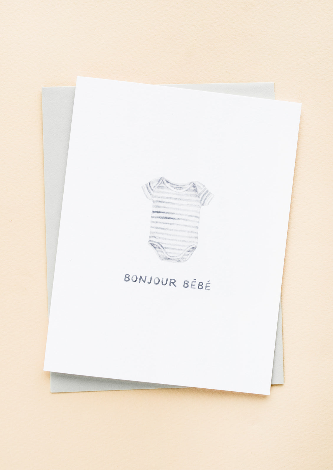 A greeting card with illustration of a striped onesie with text underneath reading "Bonjour bebe"