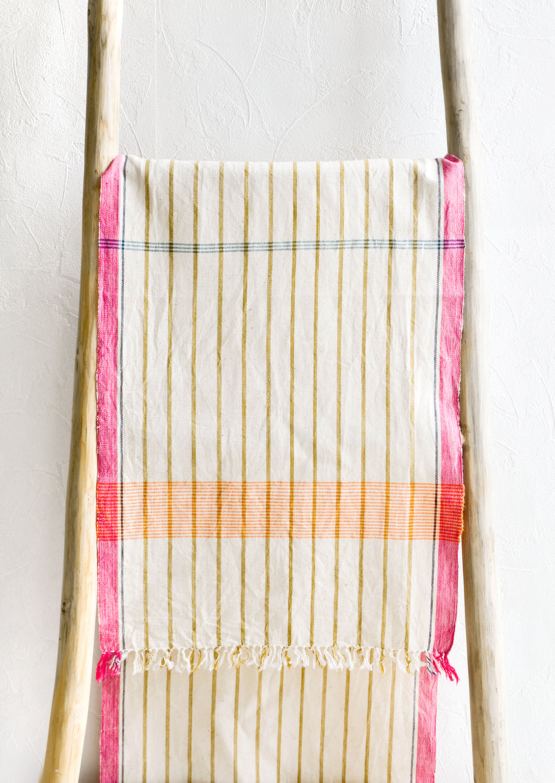 Brightly colored cotton table runner displayed on wooden ladder