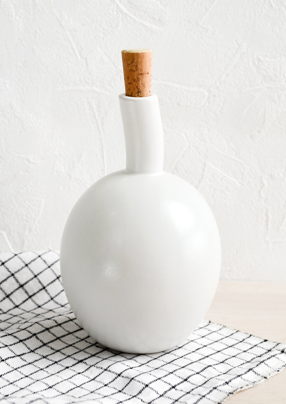 A matte white ceramic cruet bottle with asymmetrical, bulbous silhouette.