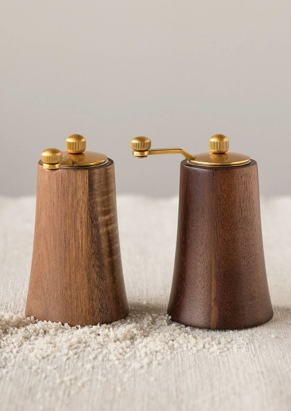 Wood salt and pepper grinders in light and dark wood tones with brass hardware.