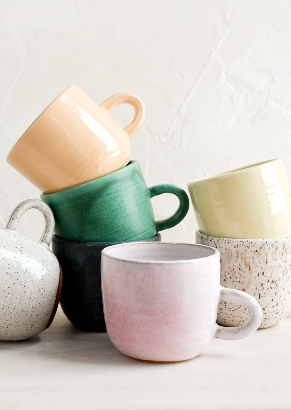 A stack of ceramic mugs in a mix of glazes and colors.