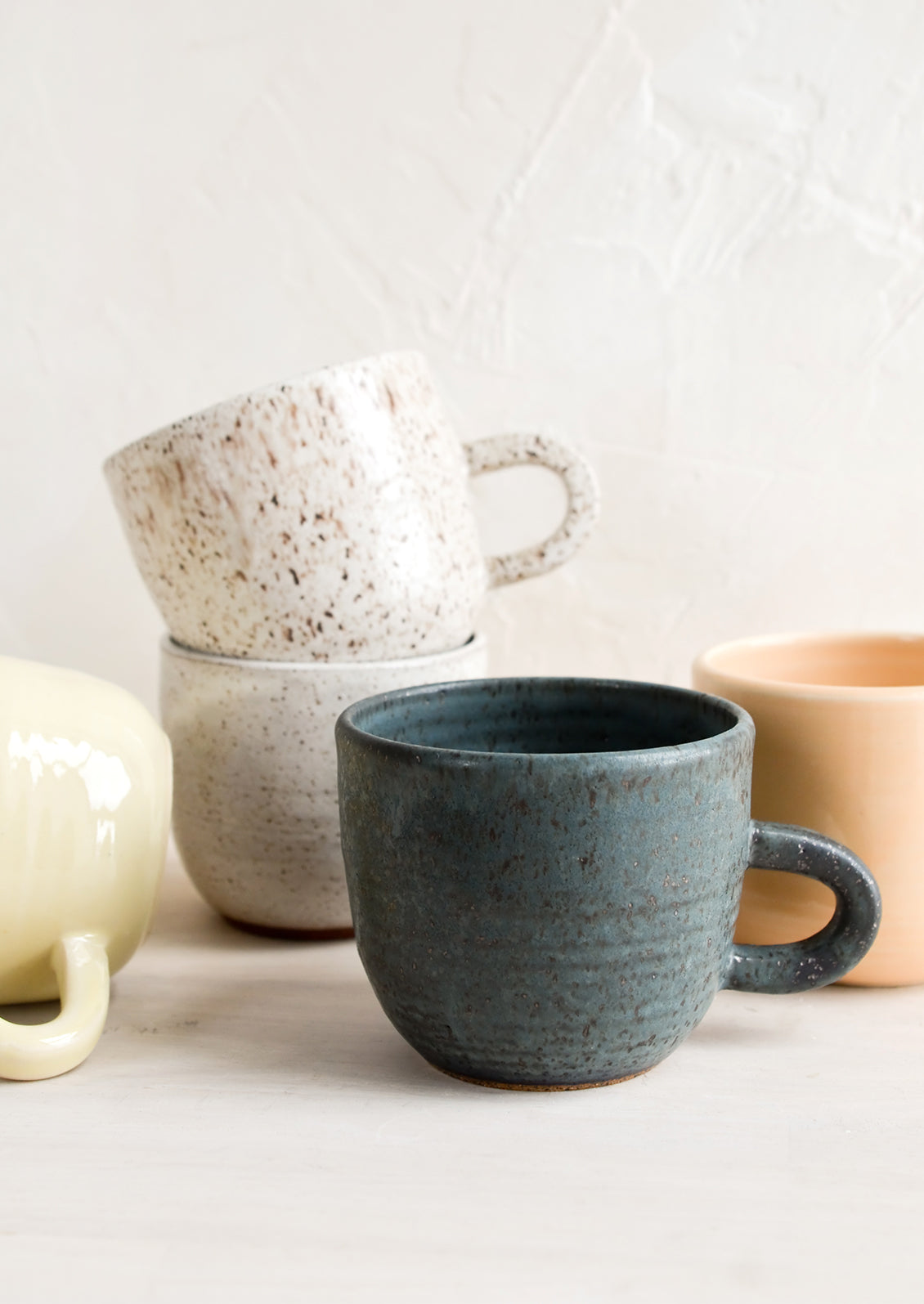 A stack of ceramic mugs in a mix of glazes and colors.