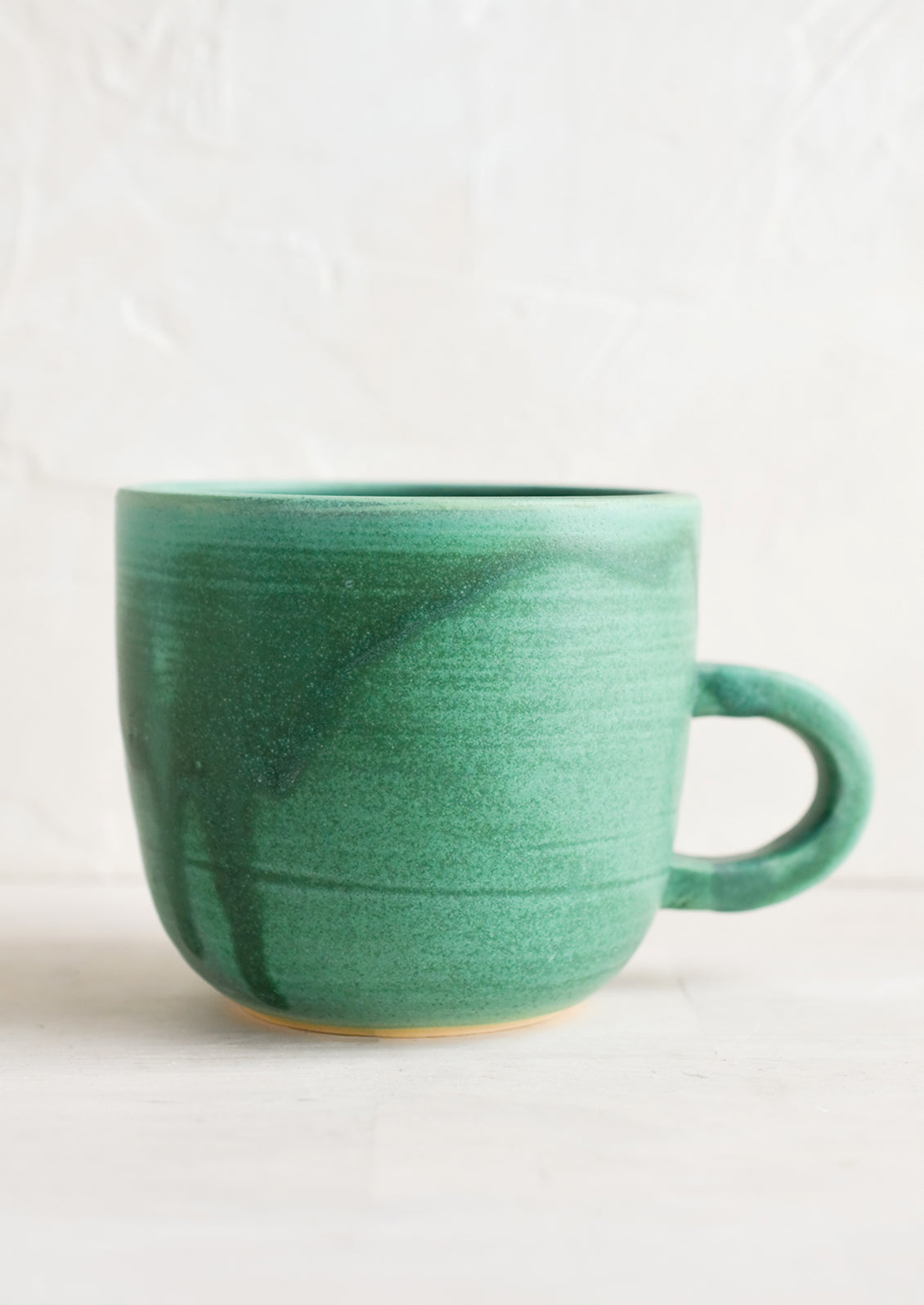 A short ceramic coffee mug in matte sea green glaze.