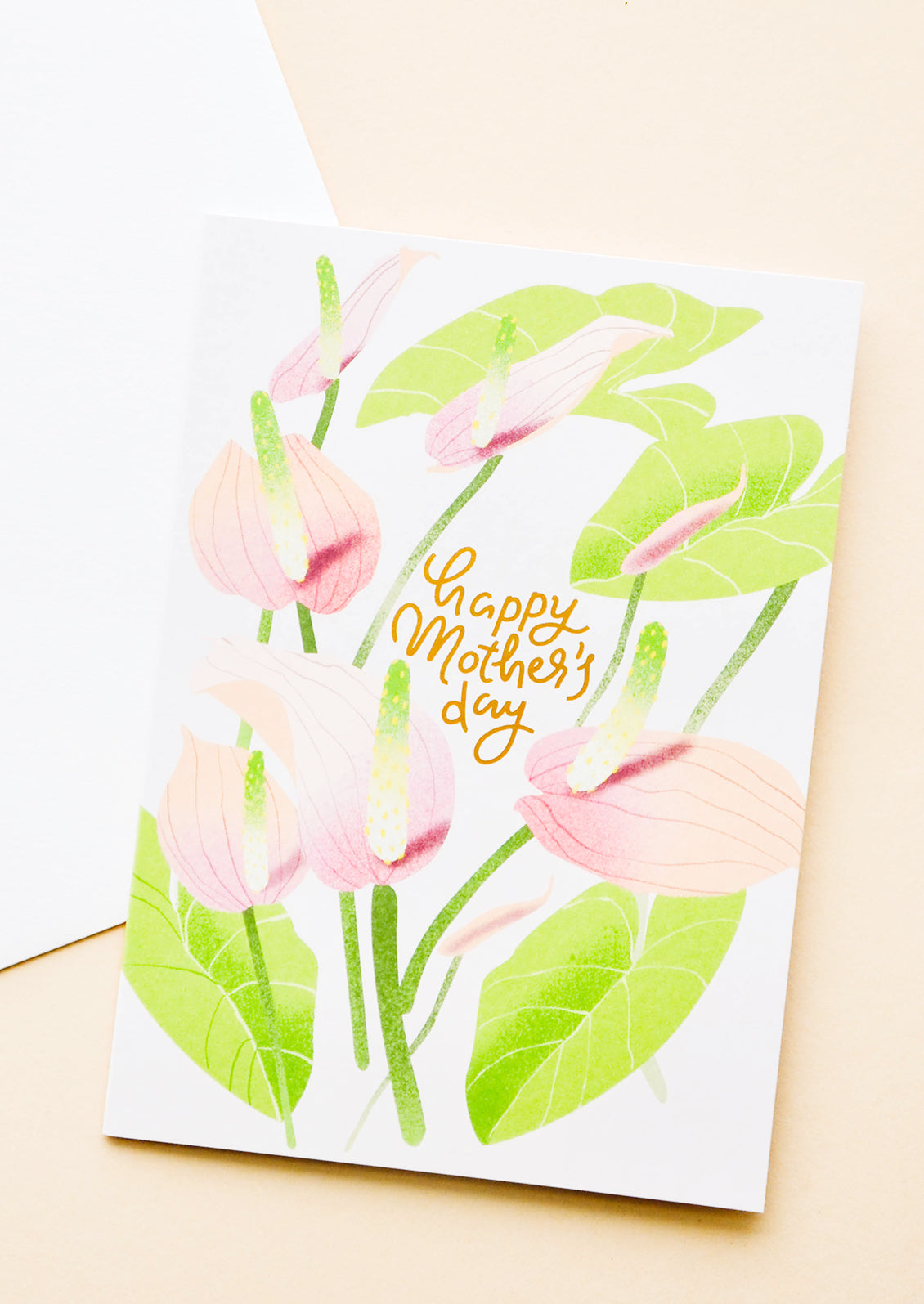 Greeting card with painted anthurium stems and "happy mothers day" written in gold. Shown with white envelope.