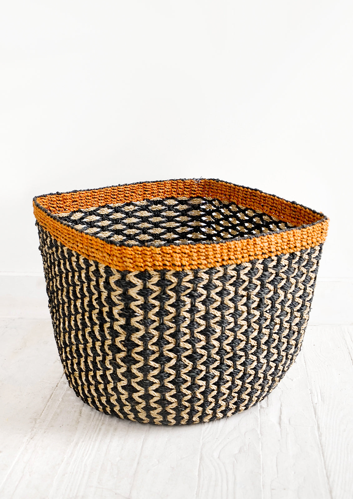 Square storage basket in black with tan zigzag design and orange top rim