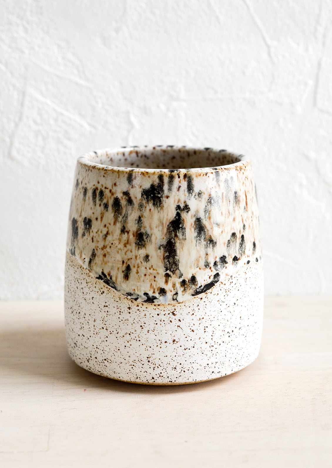 White speckled ceramic cup with mottled glaze detail.