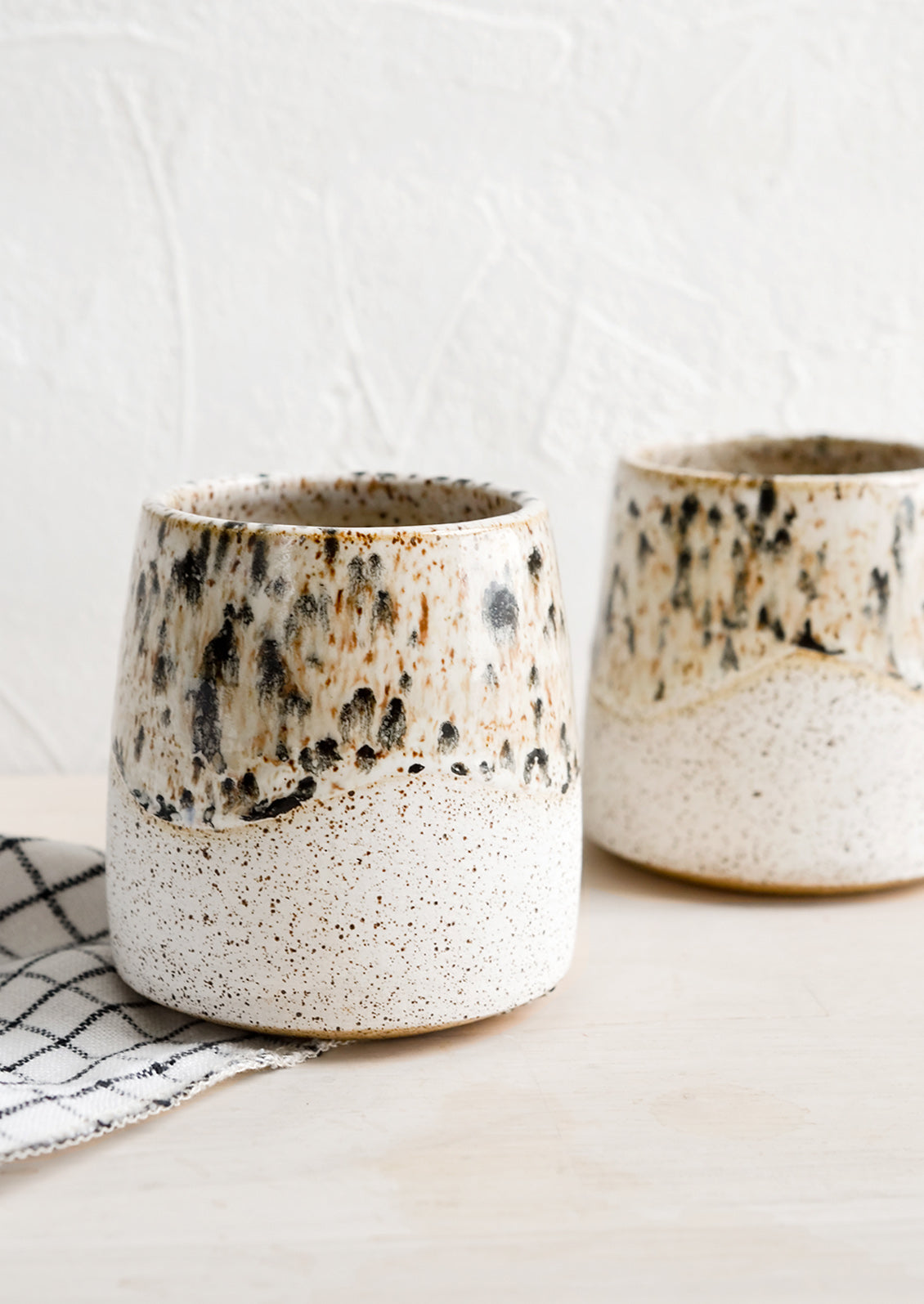 White speckled ceramic cups with mottled glaze detail.