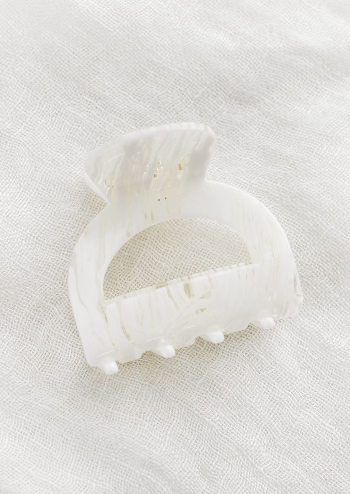 An arch shaped hair claw in spun white.