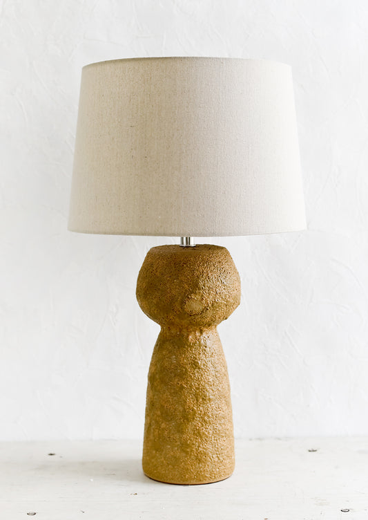A textured brown stoneware table lamp.