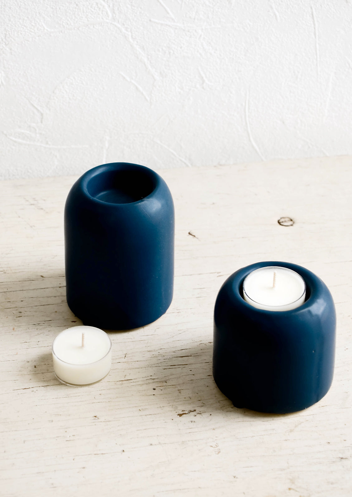 Ceramic tealight holders in jewel-tone blue, shown on table with tealights