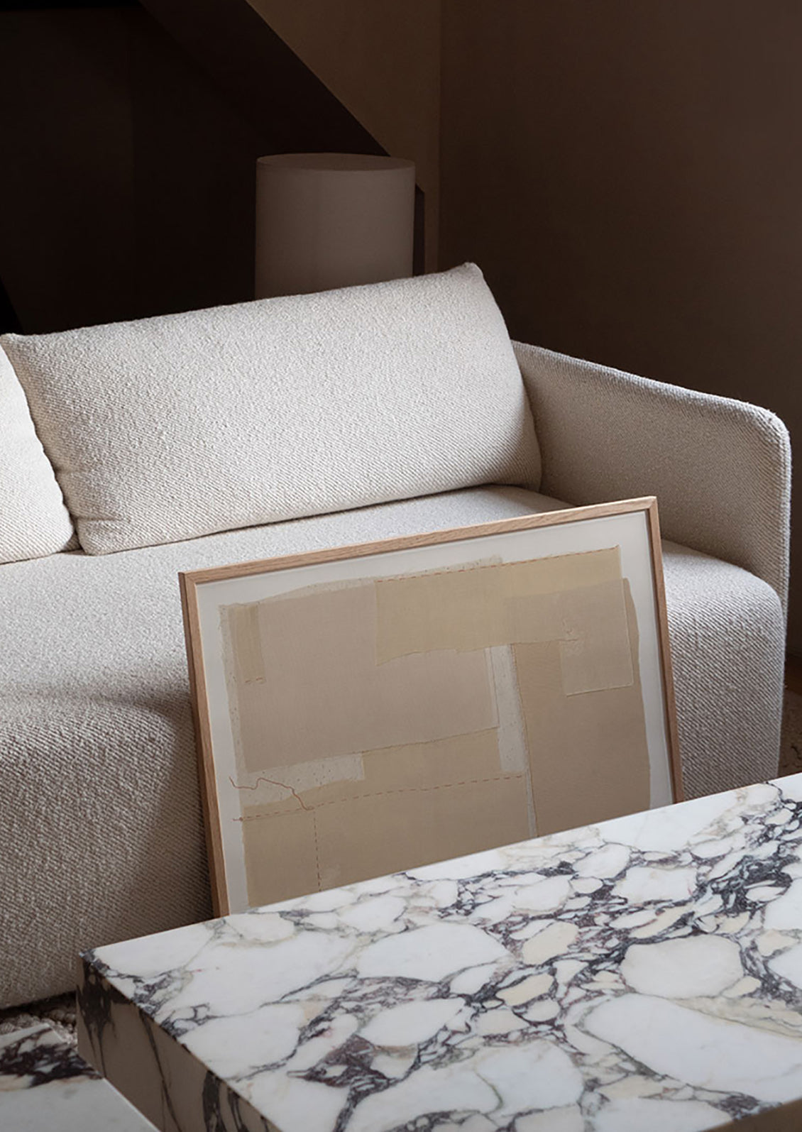 A framed art print leaning against a couch.