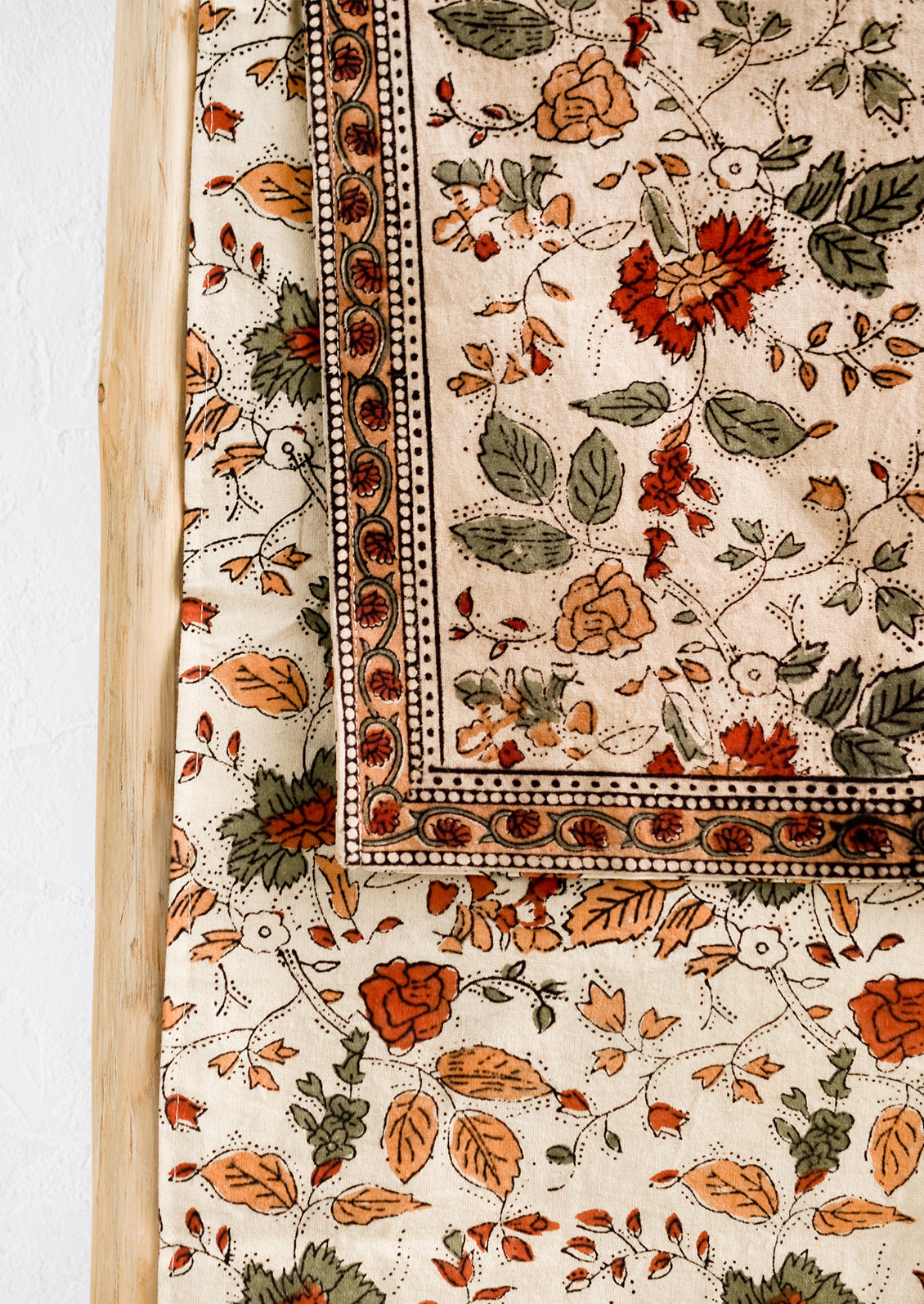 A block printed table runner in crimson, green and beige floral print.