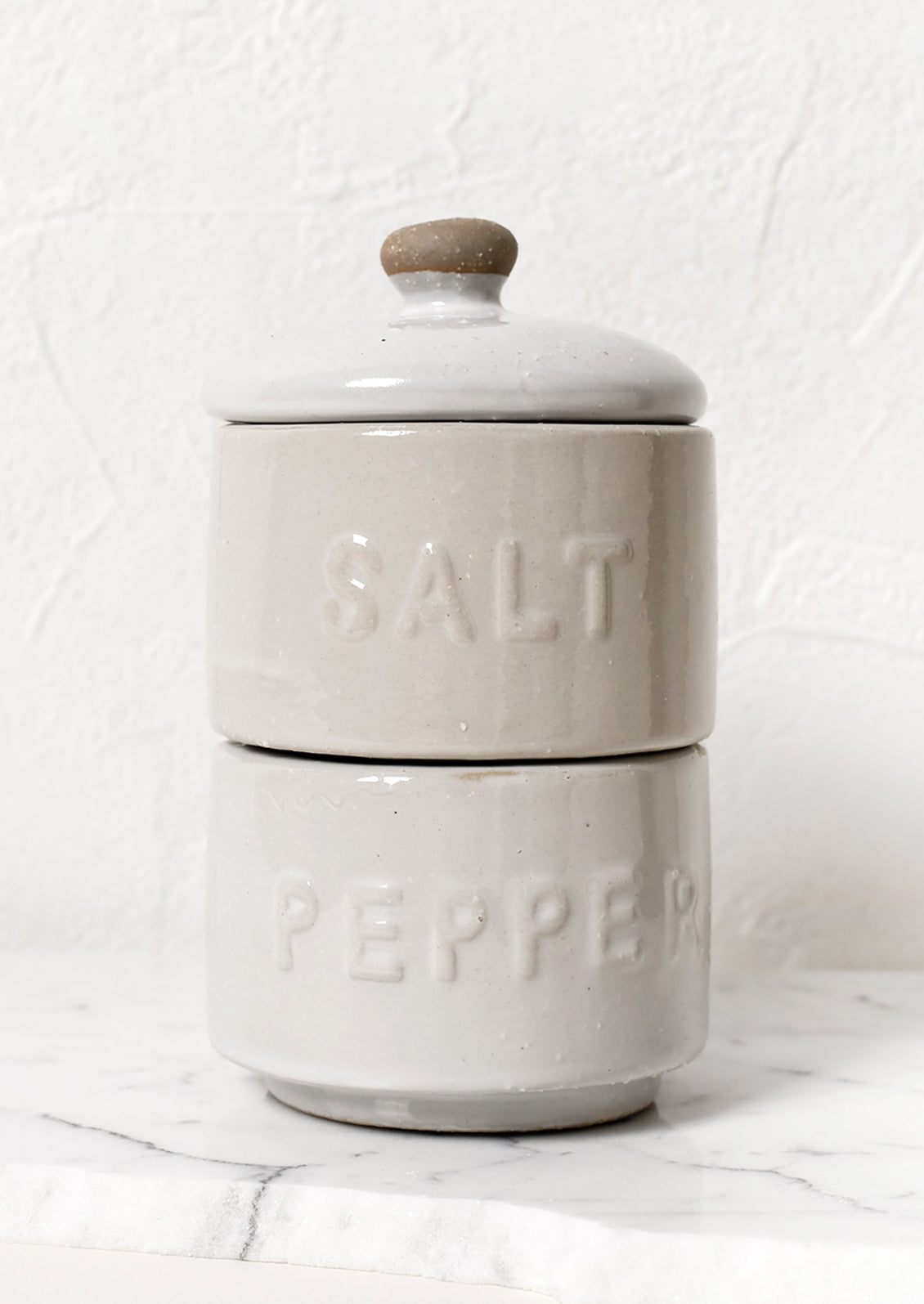 Stackable white ceramic salt and pepper jar with lid.