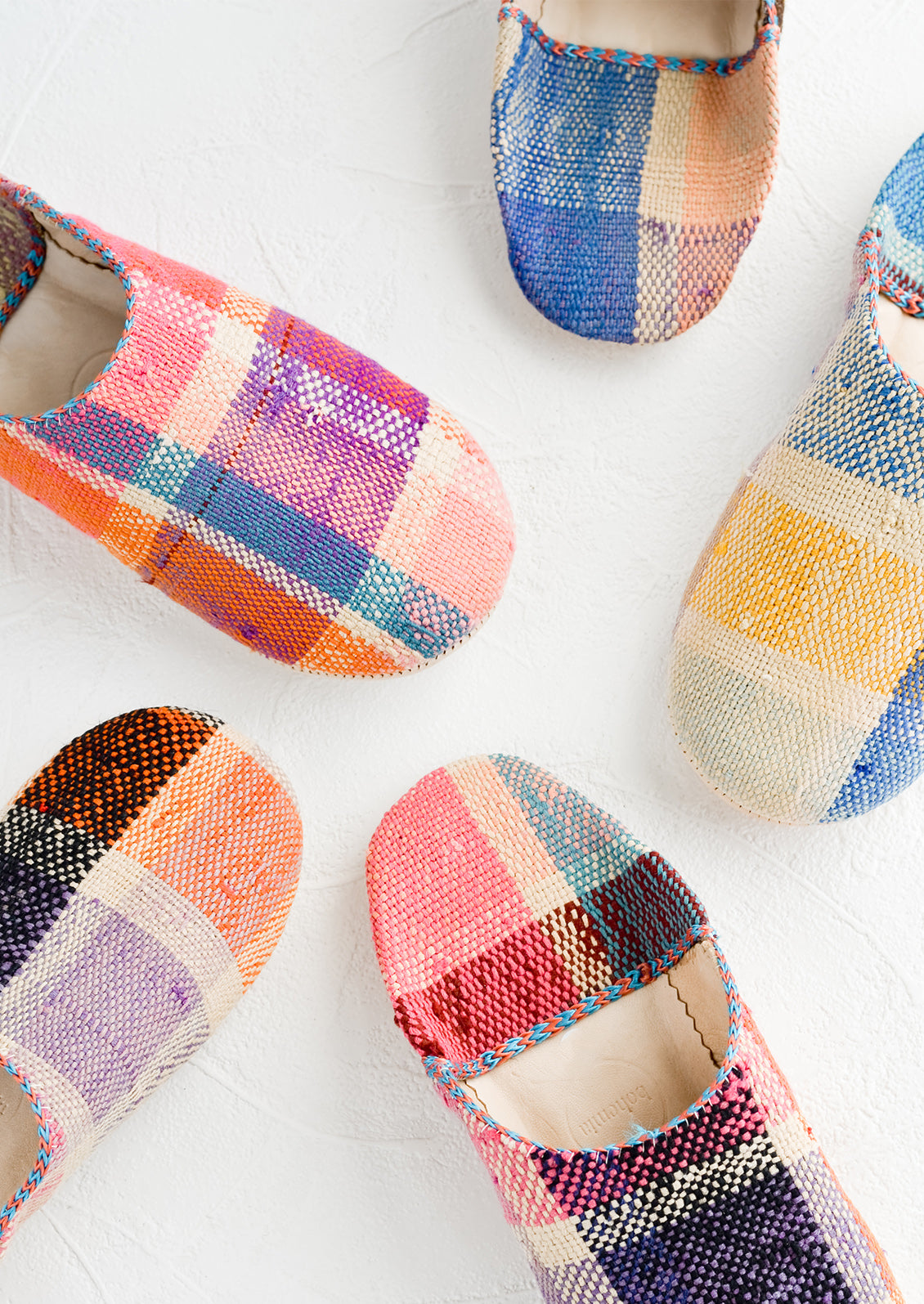 An assortment of house slippers made from colorful plaid fabric.