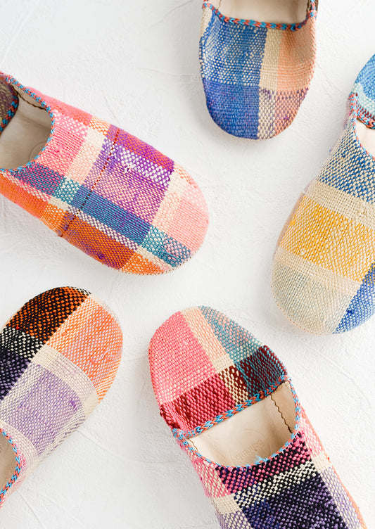An assortment of house slippers made from colorful plaid fabric.