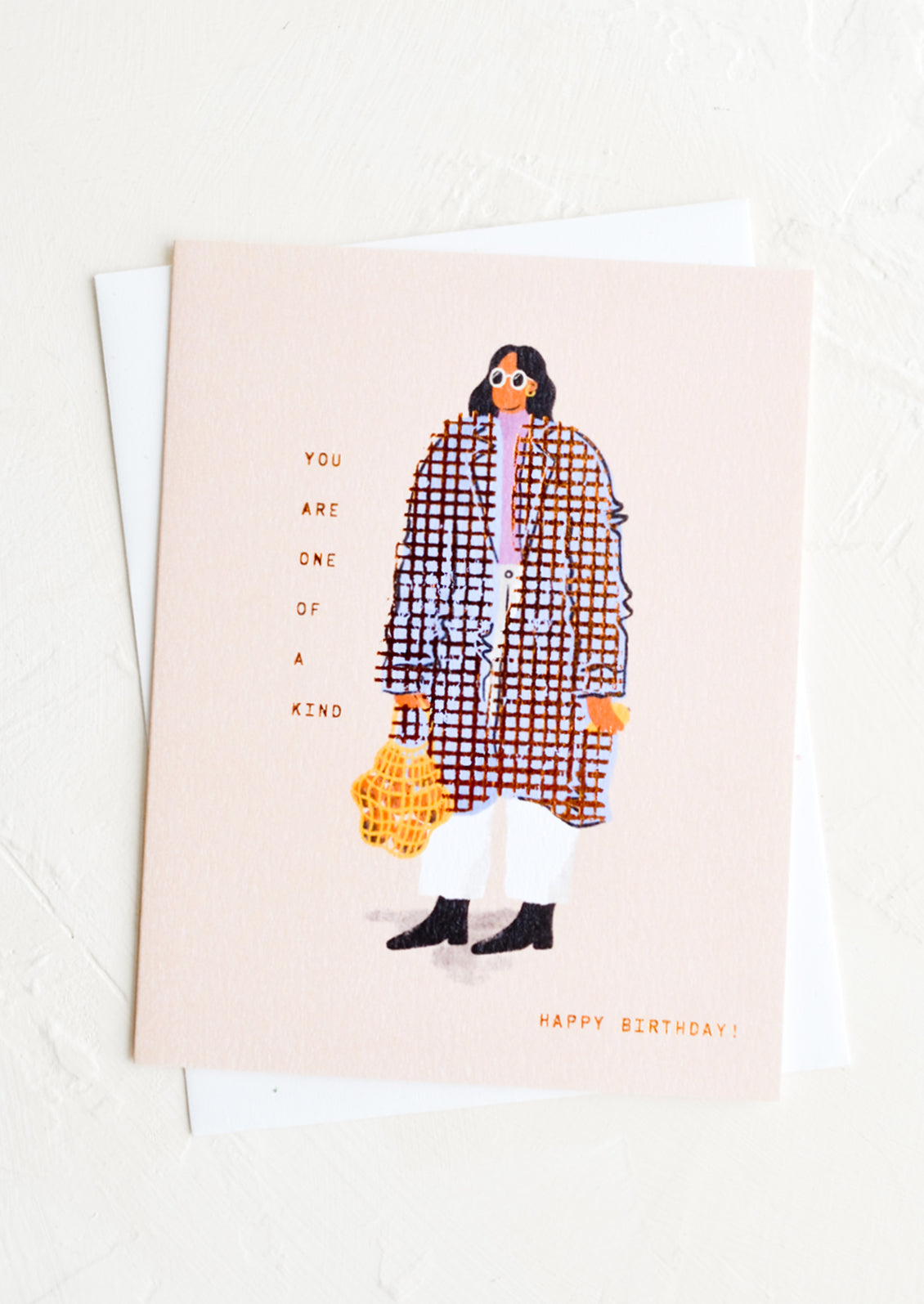 A greeting card with image of woman wearing baggy coat, text reads "You are one of a kind, happy birthday".