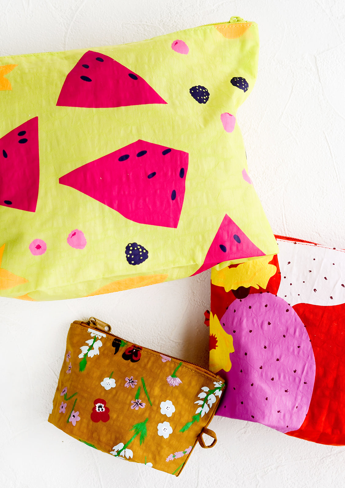 Three fruit and floral print nylon pouches in small, medium and large sizes.