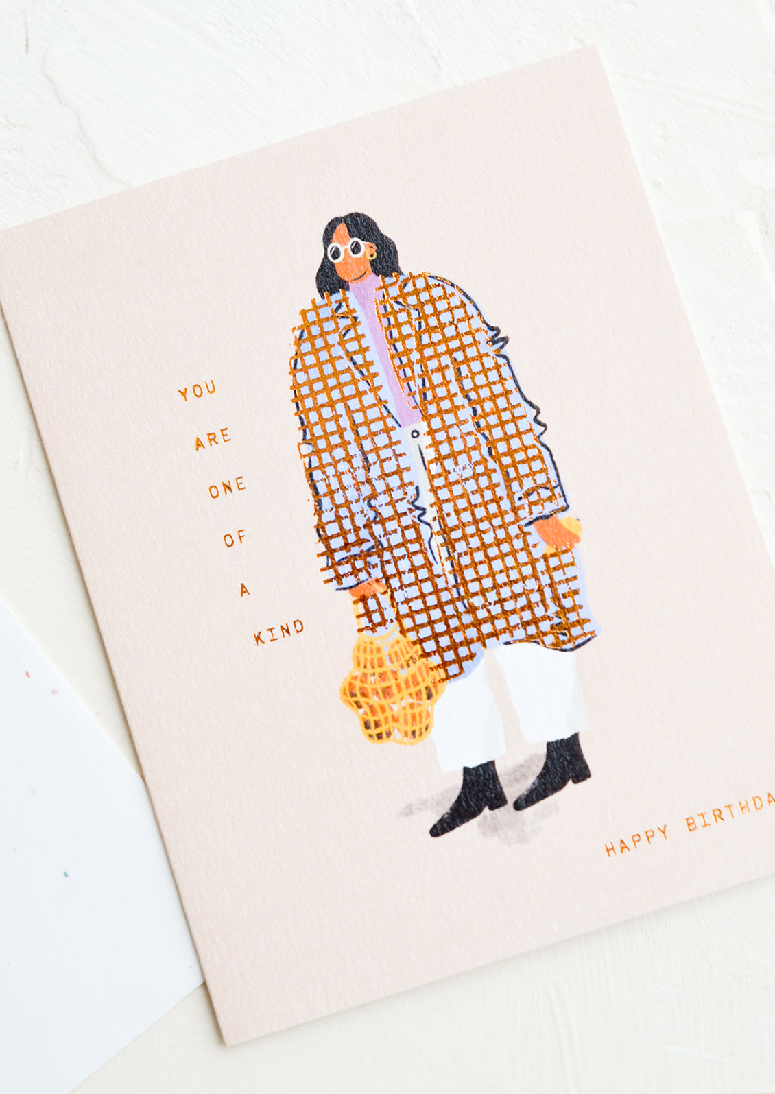 A greeting card with image of woman wearing baggy coat, text reads "You are one of a kind, happy birthday".