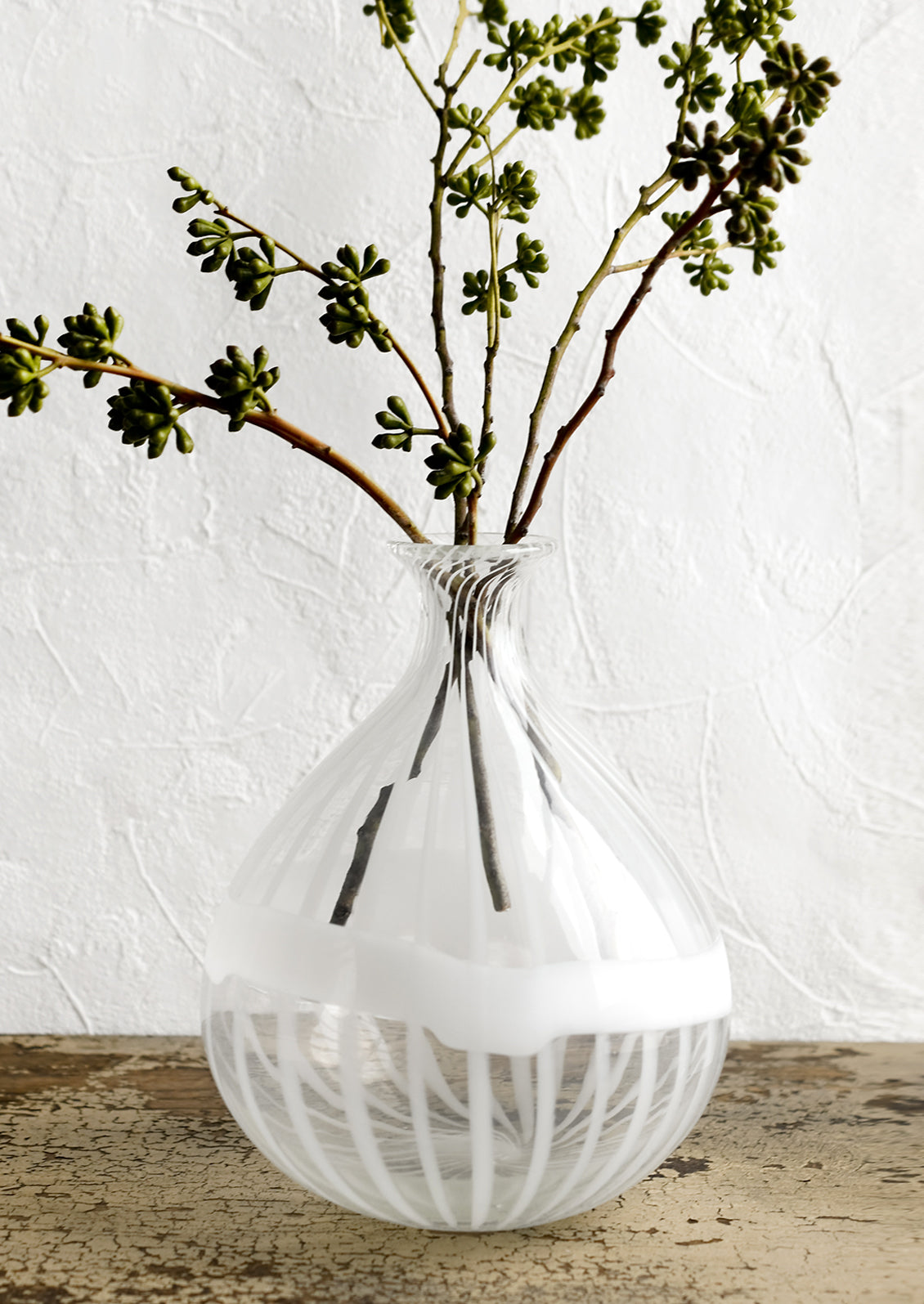 A clear balloon shaped glass vase with white stripe banding.