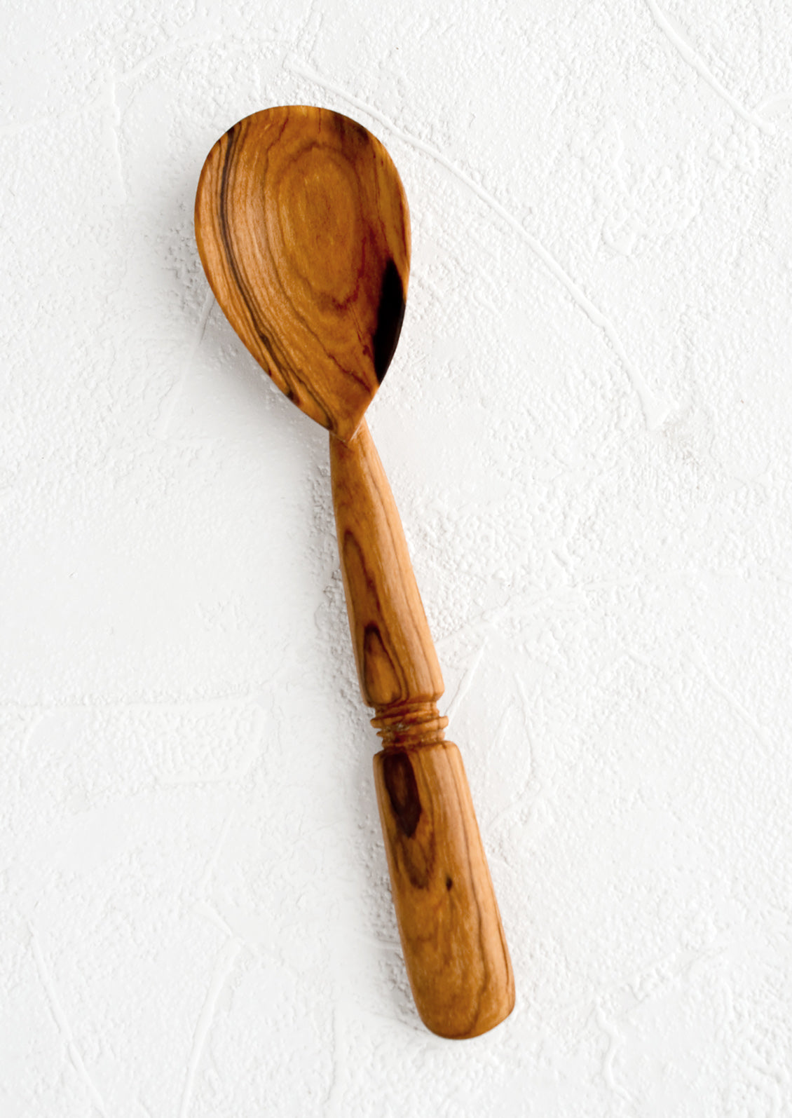 A hand carved spoon with inset "band" detailing on handle.