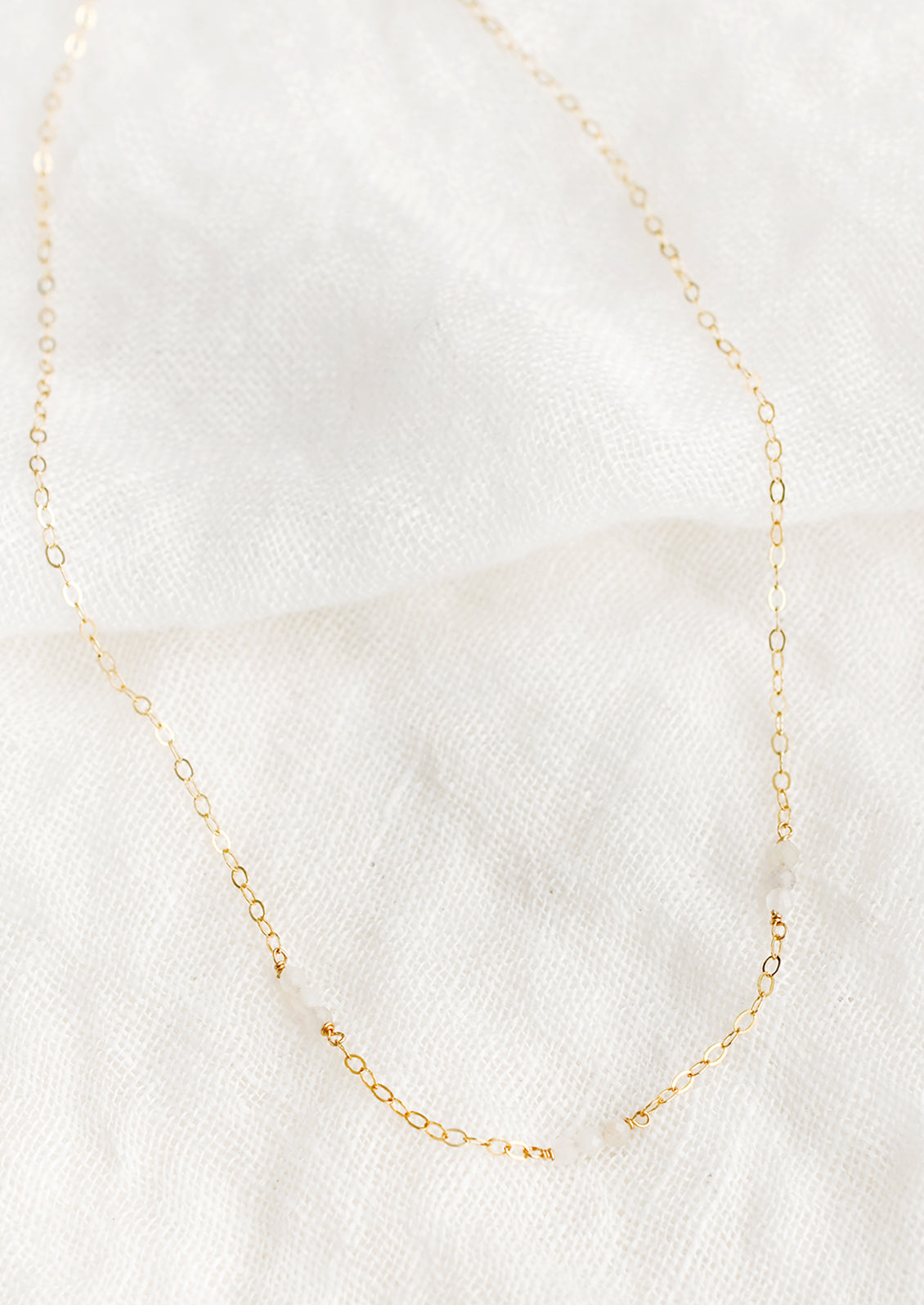 A delicate gold chain necklace with moonstone beaded stations.
