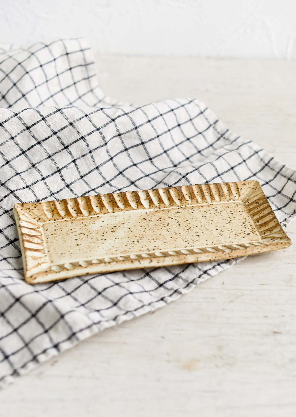 A rectangular ceramic butter plate on a tea towel.